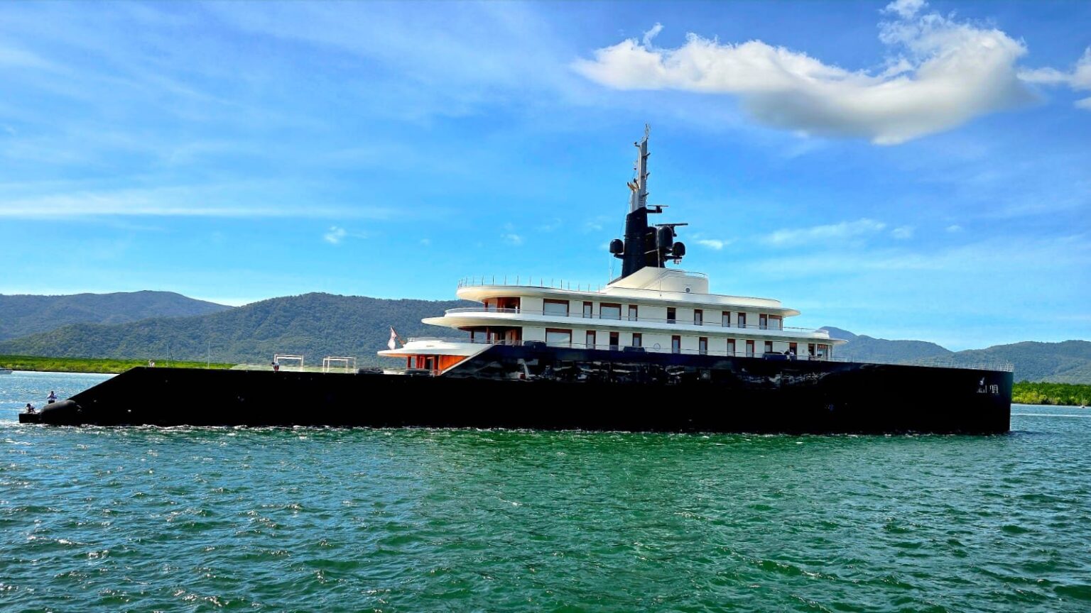 Superyacht underway in Cairns with the rainforest ranges behind