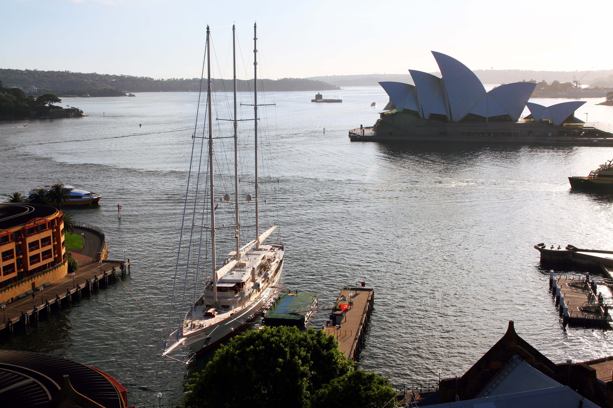Sailing superyacht on Sydney Harbour at dawn with the Opera House beyond
